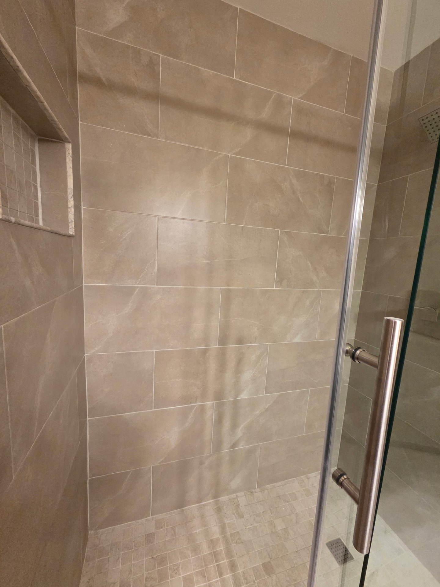 Finished tiled shower with built-in niche and mosaic floor