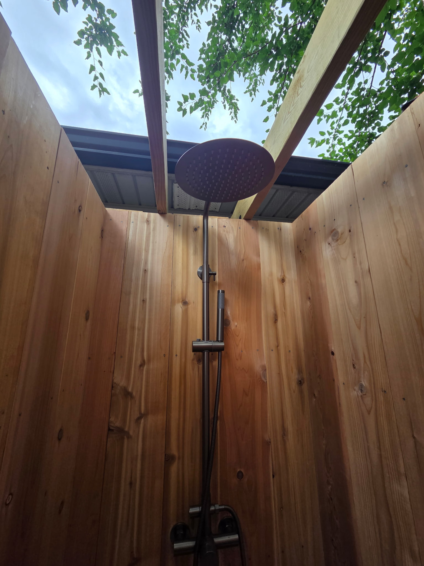 Rainfall shower head inside a cedar outdoor shower