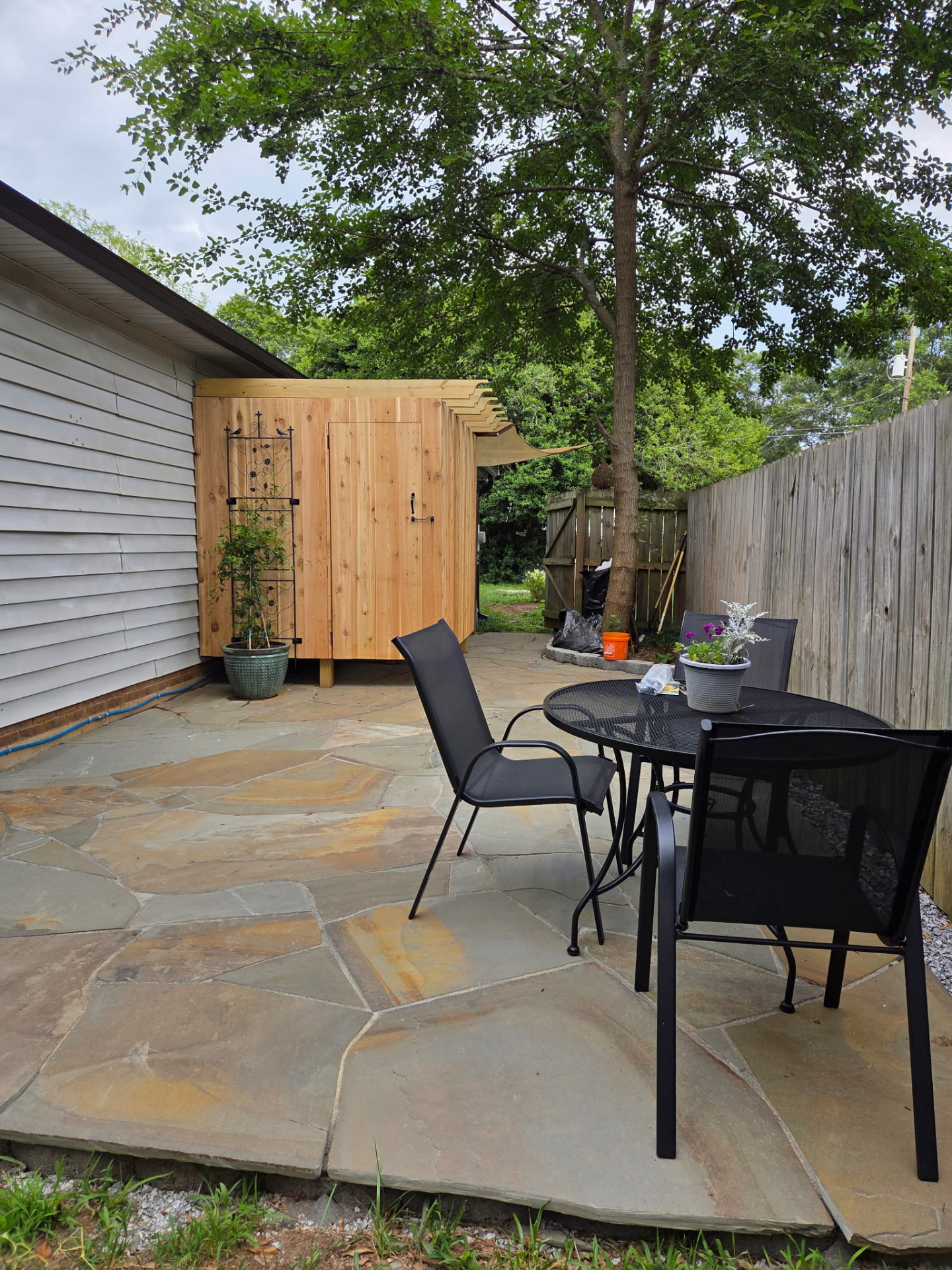Flagstone patio with dining set beside a new cedar outdoor shower