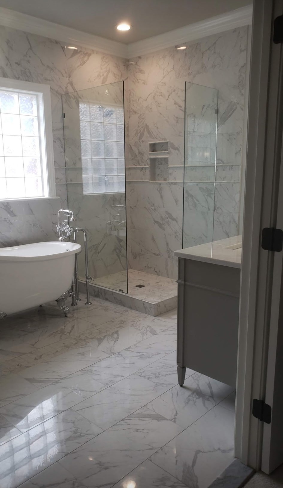 Marble-tiled master bathroom with frameless glass shower and clawfoot tub
