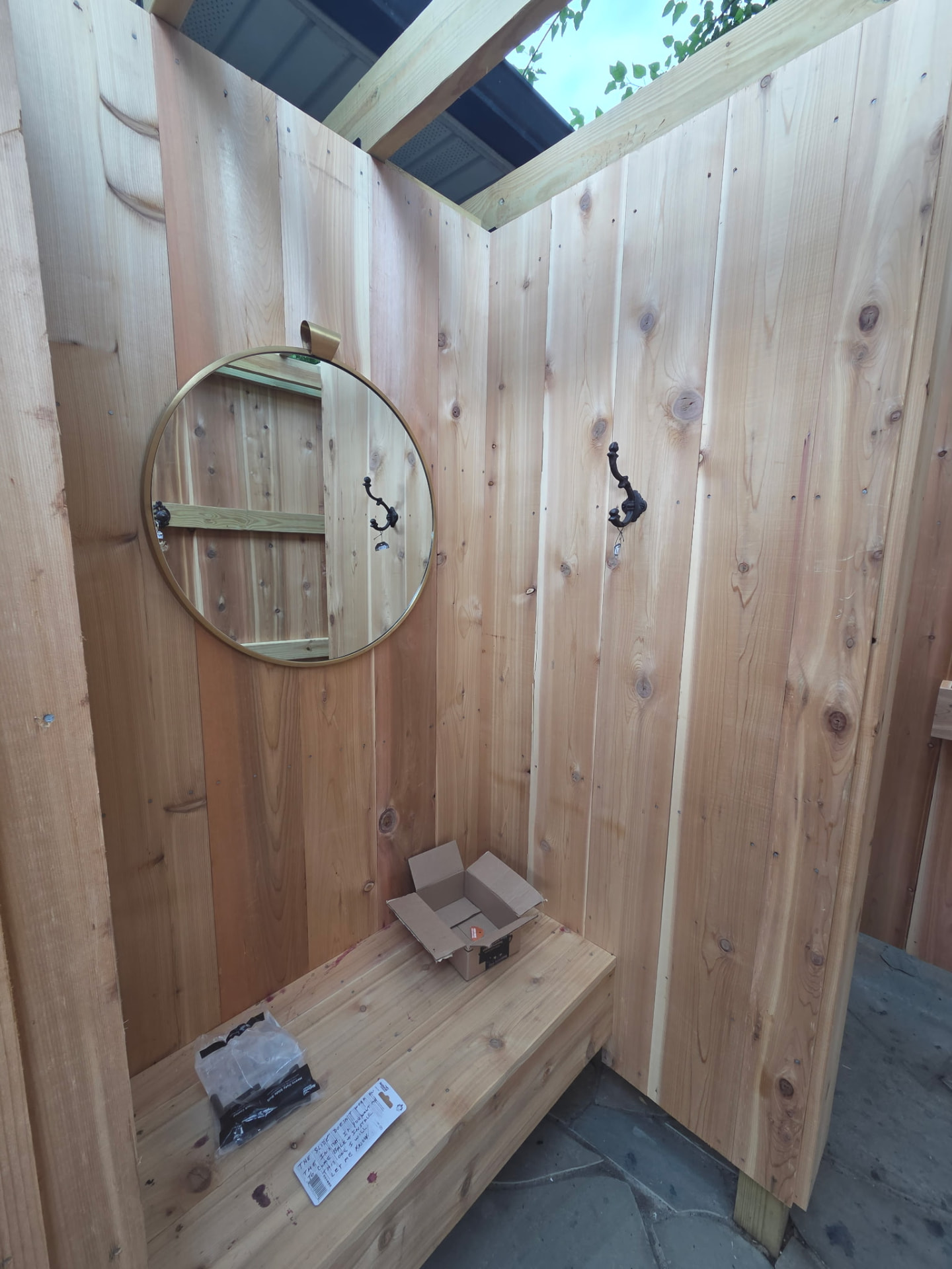 Cedar outdoor shower interior with built-in bench, mirror and hooks