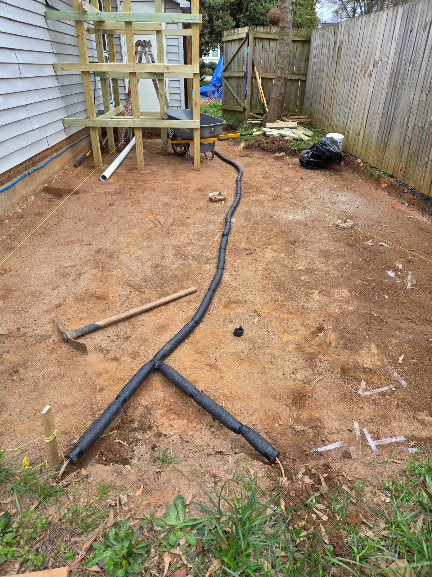 Graded and staged backyard patio site with drainage lines laid out